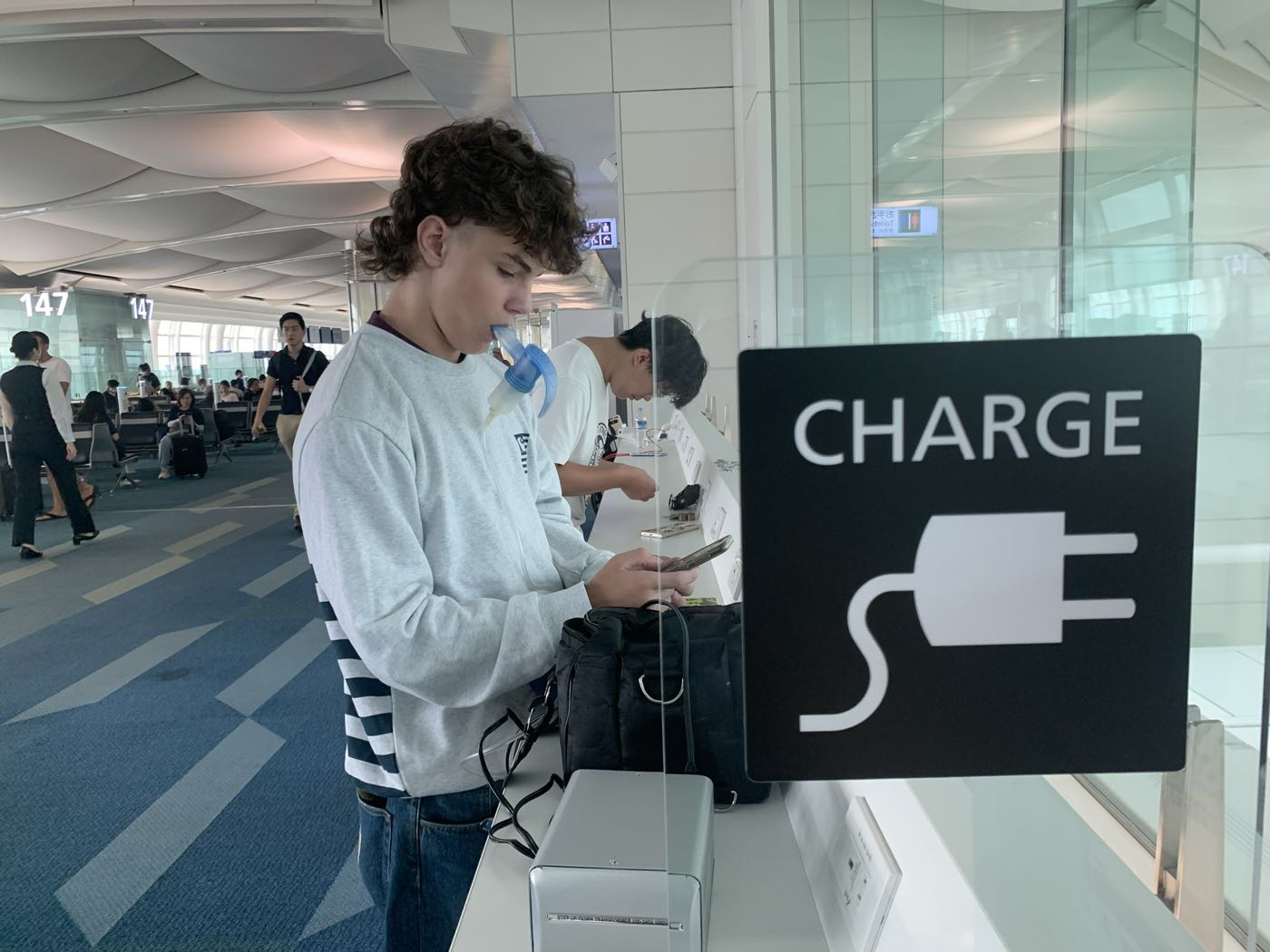 Jugendlicher inhaliert an einer Ladestation am Flughafen während einer Fernreise
