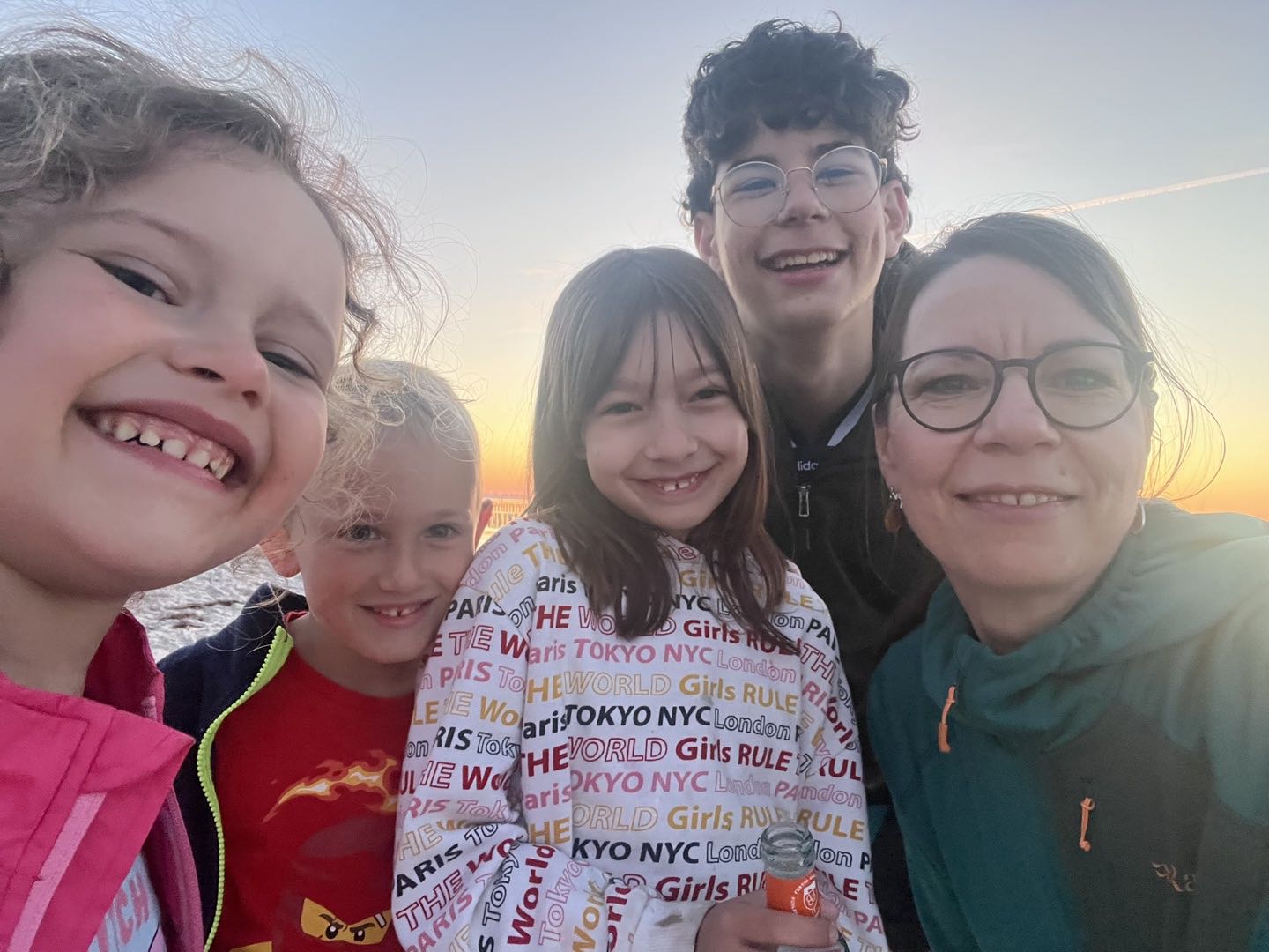 Fröhliches Familien-Selfie mit lachenden Kindern und Jugendlichen im warmen Abendlicht