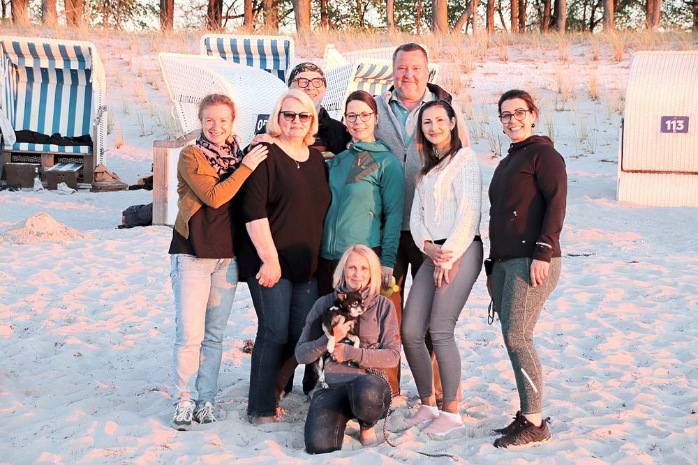 Gruppe des Vorstands und Beirats mit Hund am Strand vor Strandkörben im Abendlicht